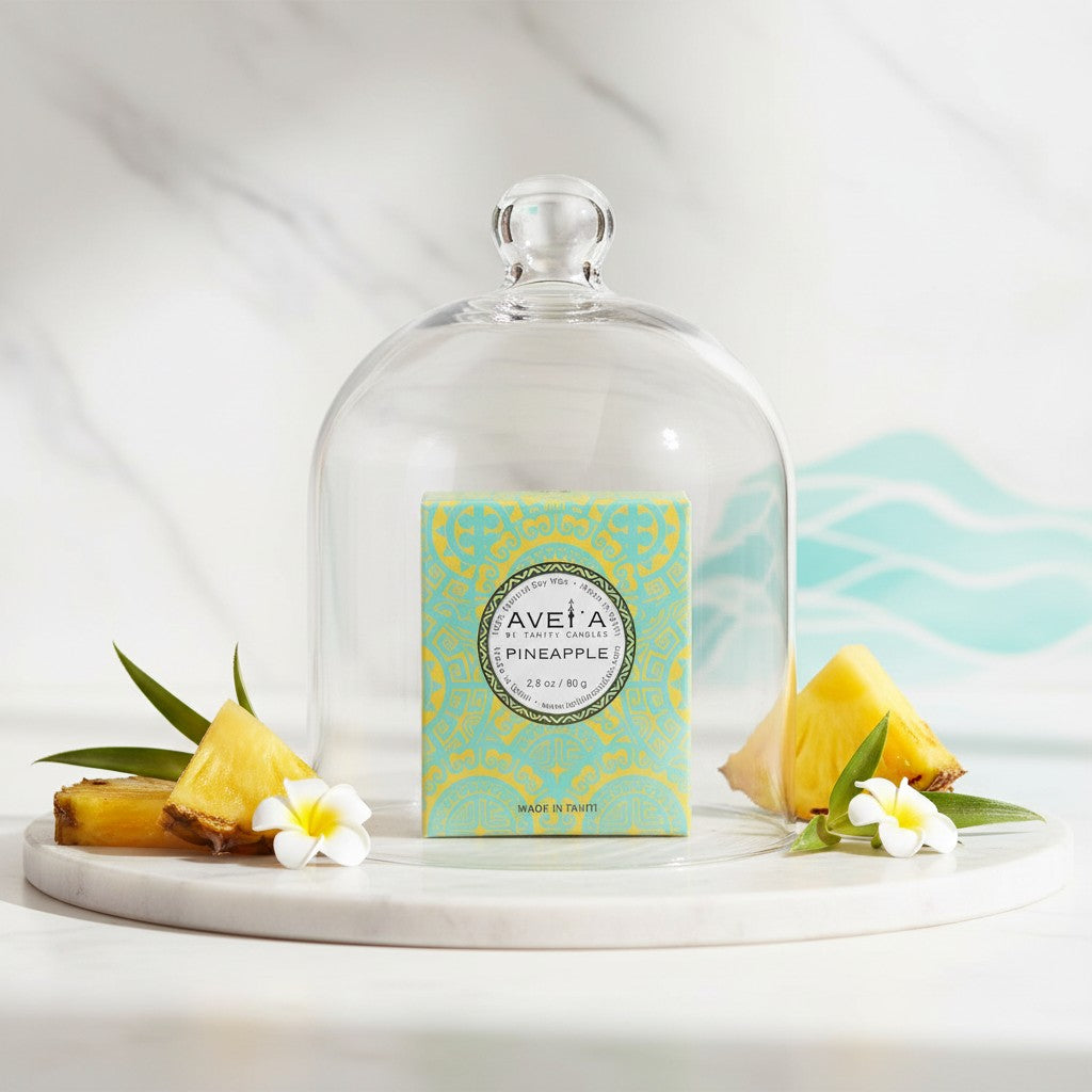 Bougie parfumée Tahiti Candles Pineapple 80g dans son emballage turquoise sous une cloche en verre avec ananas frais