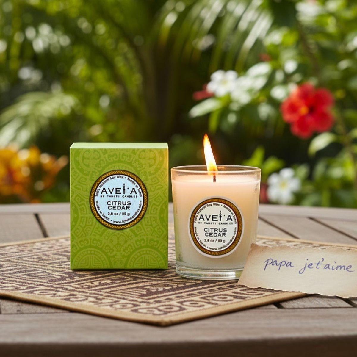 Bougie parfumée Tahiti Candles Citrus Cedar 80g en pot de verre avec boîte verte sur une table en bois en extérieur
