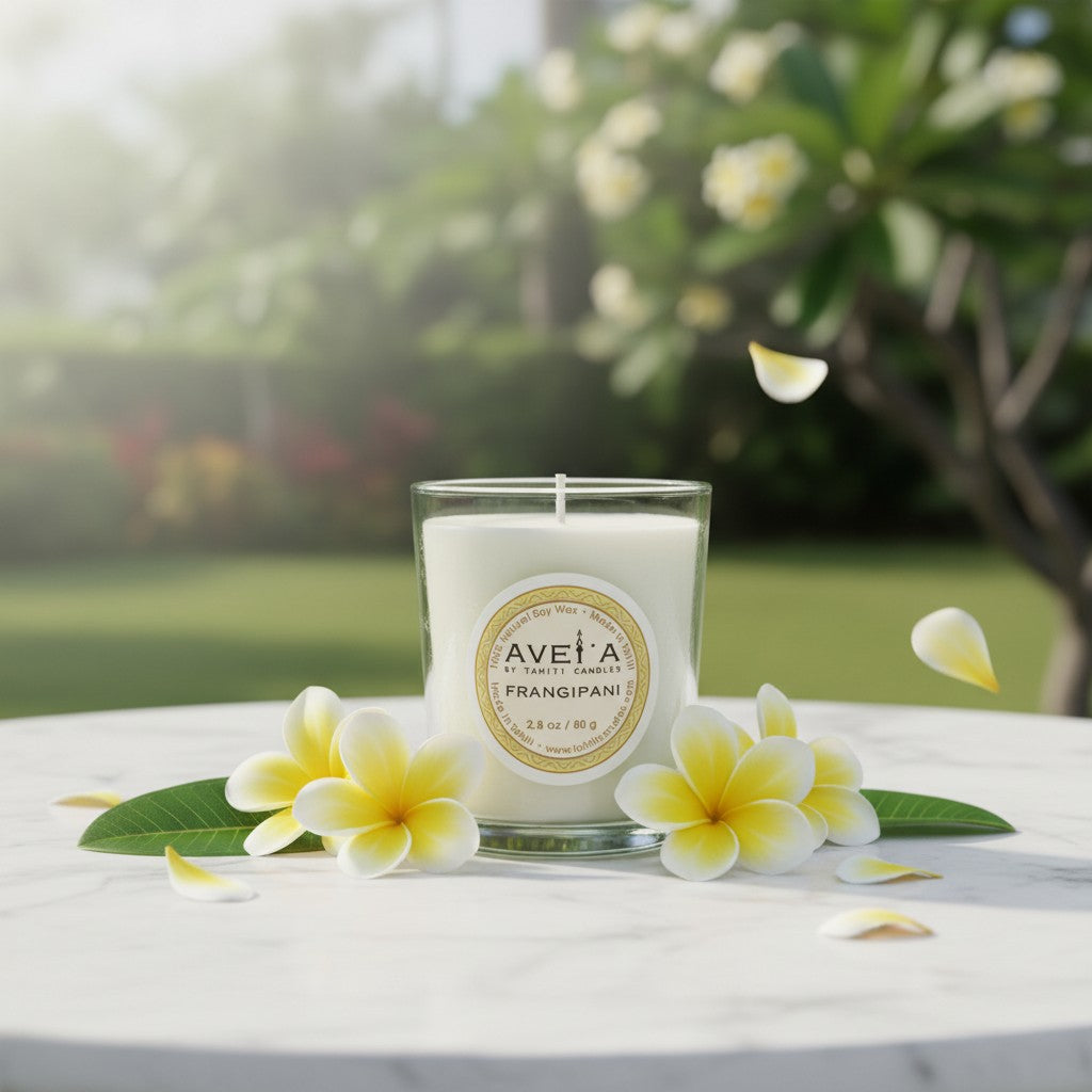 Bougie parfumée Tahiti Candles Frangipani 80g en pot de verre, entourée de fleurs de frangipanier sur une table en marbre