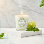 Bougie parfumée Tahiti Candles Lime Basil en pot de verre avec citron vert et basilic frais sur socle blanc