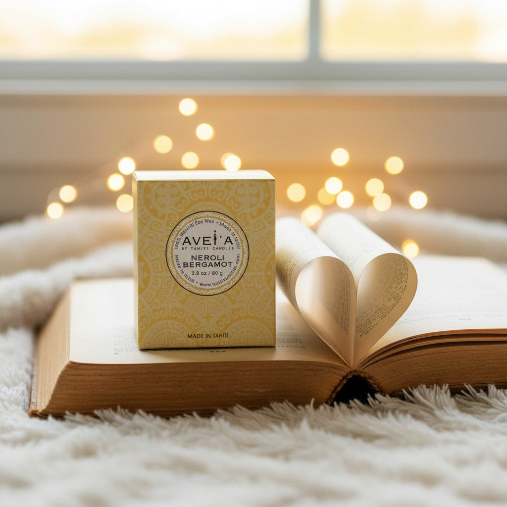 Bougie parfumée Tahiti Candles Neroli Bergamot 80g dans son emballage jaune décoratif posée sur un livre ouvert