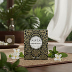 Bougie parfumée Tahiti Candles au bois de santal dans son emballage décoré de motifs polynésiens sur un tapis en bambou