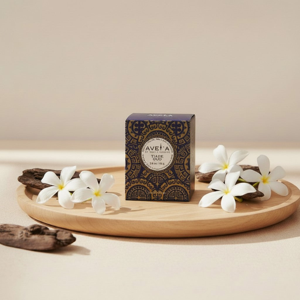 Bougie parfumée Tahiti Candles Tiare Oud 80g dans son emballage bleu orné de motifs polynésiens sur un plateau en bois