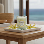 Bougie parfumée Tahiti Candles Ylang Ylang 80g en pot de verre blanc sur plateau avec fleurs jaunes exotiques