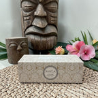 Coffret cadeau Tahiti Candles de 3 bougies artisanales dans une boîte décorée aux motifs polynésiens sur un set en osier