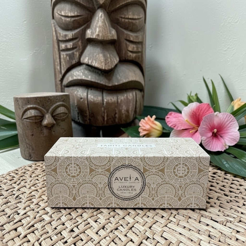 Coffret cadeau Tahiti Candles de 3 bougies artisanales dans une boîte décorée aux motifs polynésiens sur un set en osier